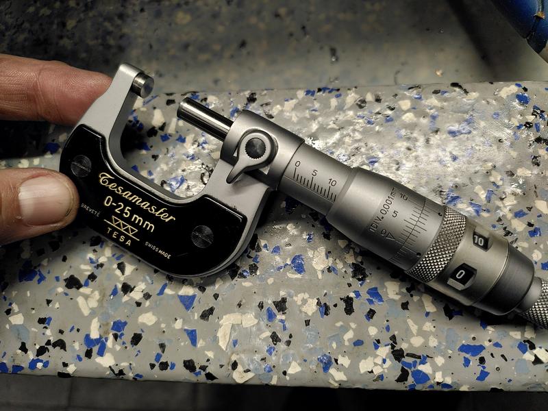 A Tesamaster 0-25mm micrometer showing 12.003mm. The micrometer is being
held by a finger and thumb to the left of shot.